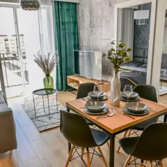 Nowoczesne mieszkania w Nowej Soli: salon z jadalnią, wygodna sofa, stół z krzesłami i widokiem na balkon.