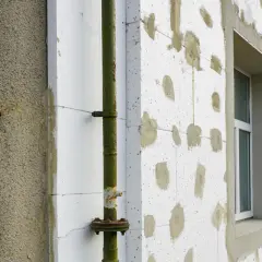 Budynek w trakcie termoizolacji styropianem. Zastanawiasz się, ile kosztuje termoizolacja budynku? Widoczna rura i okno.