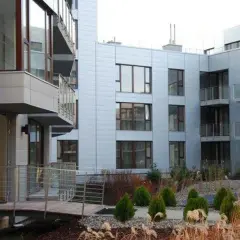 Nowoczesne budynki mieszkalne Triton Park Apartments z balkonami i dużymi oknami, otoczone zadbaną zielenią.
