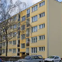 Żółty blok mieszkalny, zimowy dzień. Warto wiedzieć, jak zdać mieszkanie komunalne po śmierci najemcy.