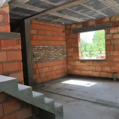 Budynek gospodarczy w trakcie adaptacji na cele mieszkalne. Widoczne schody betonowe, ściany z pustaków ceramicznych i betonowych, otwór okienny.