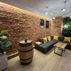 Nowoczesny lokal do wynajęcia Lublin. Ceglana ściana, wygodna kanapa, beczka jako stolik i zielona ściana.