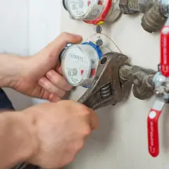 Instalator dokręca kluczem wodomierz, który wymaga wymiany. Sprawdź, co ile wymienia się wodomierze, by uniknąć problemów.