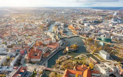 Widok z lotu ptaka na Wrocław z Odrą i licznymi mostami. Widać zabytkowe kamienice i nowoczesne budynki, idealne miejsca na mieszkania na sprzedaż Wrocław.