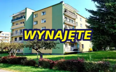 Blok mieszkalny z balkonami, zielony teren. Napis "WYNAJĘTE" sugeruje, że szukasz mieszkań do wynajęcia Zamość.