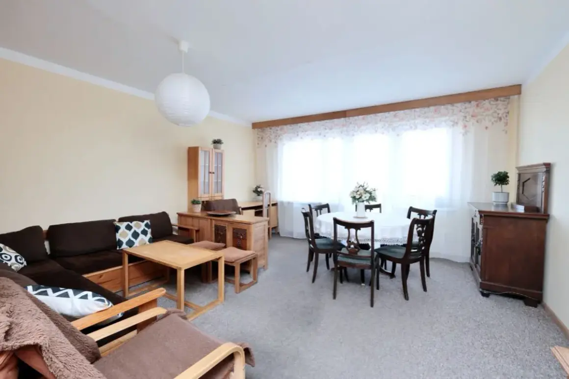 Przytulny salon z jadalnią, idealny na mieszkania do wynajęcia Płock. Duża kanapa, stół z krzesłami i stylowe meble.