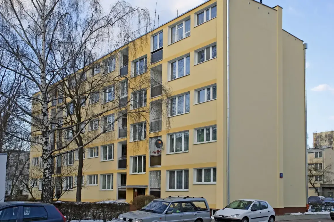 Żółty blok mieszkalny, zimowy dzień. Warto wiedzieć, jak zdać mieszkanie komunalne po śmierci najemcy.