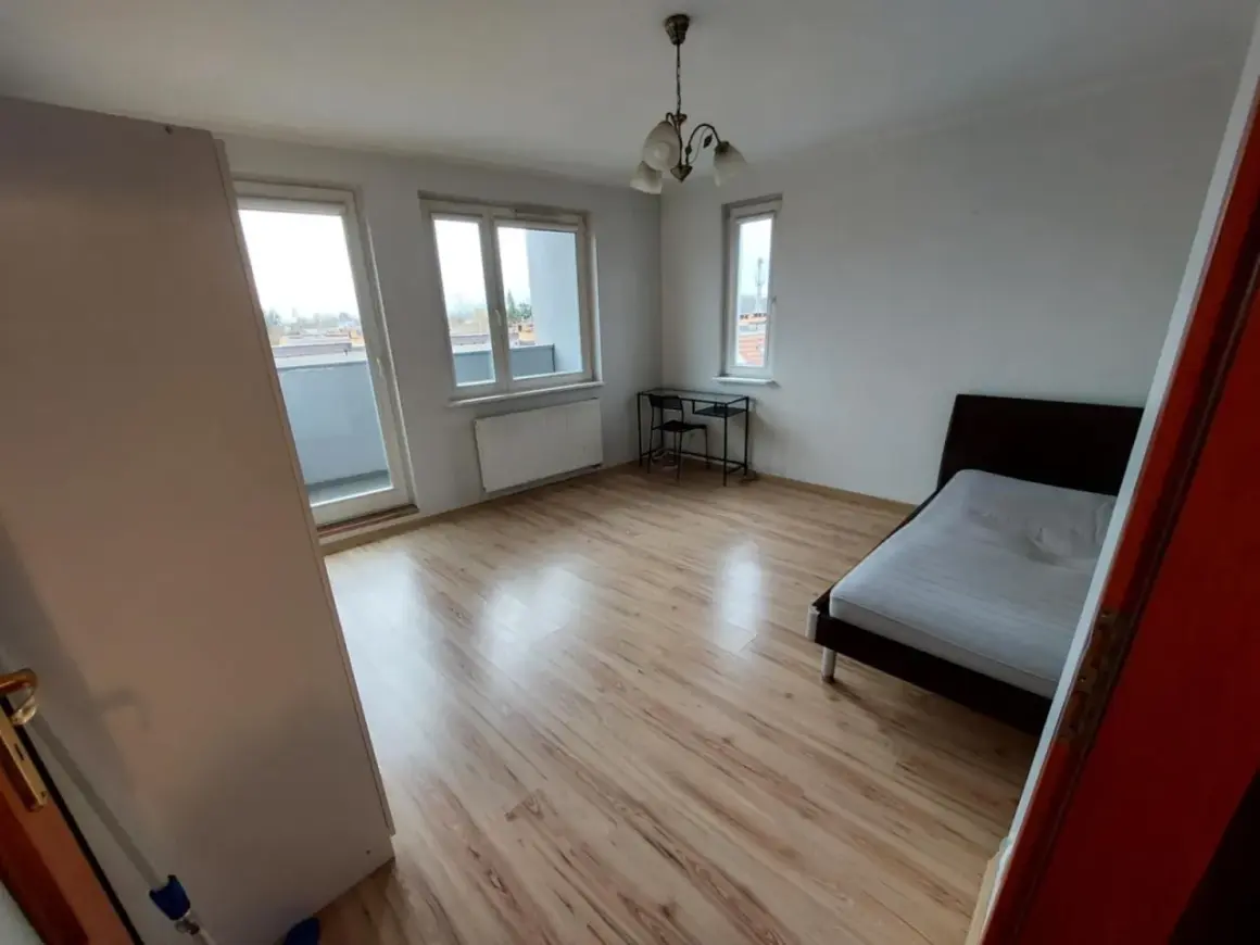 Pokój do wynajęcia Wrocław. Jasne, przestronne wnętrze z łóżkiem, biurkiem i balkonem. Idealne dla studenta lub pracownika.