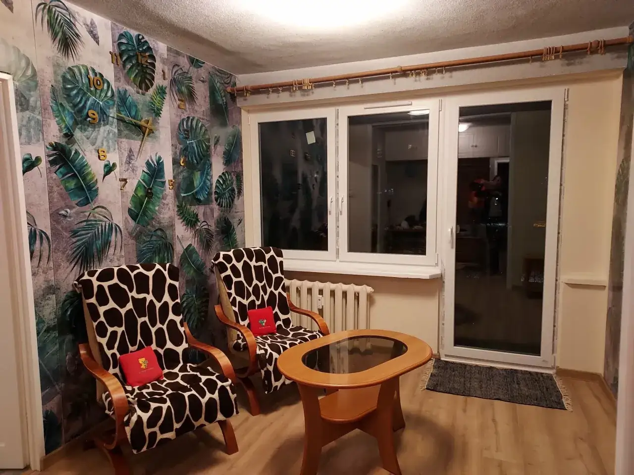 Przytulny salon z fotelami w panterkę i tropikalną tapetą. Idealne miejsce na relaks w Tarnobrzegu. Szukasz mieszkania do wynajęcia Tarnobrzeg?